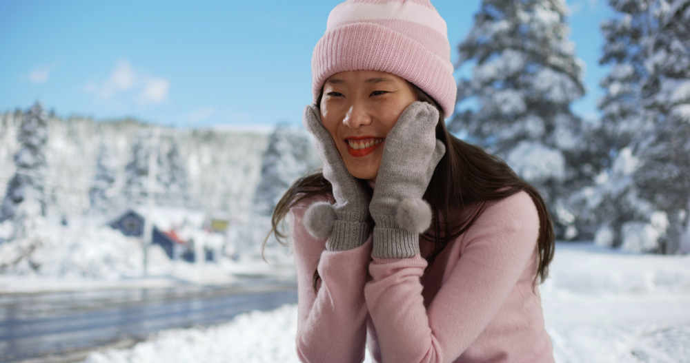 Close,Up,Of,Cute,Woman,Sitting,With,Mittens,And,Beanie Featured image showing a happy woman enjoying a snowy day in Truckee.