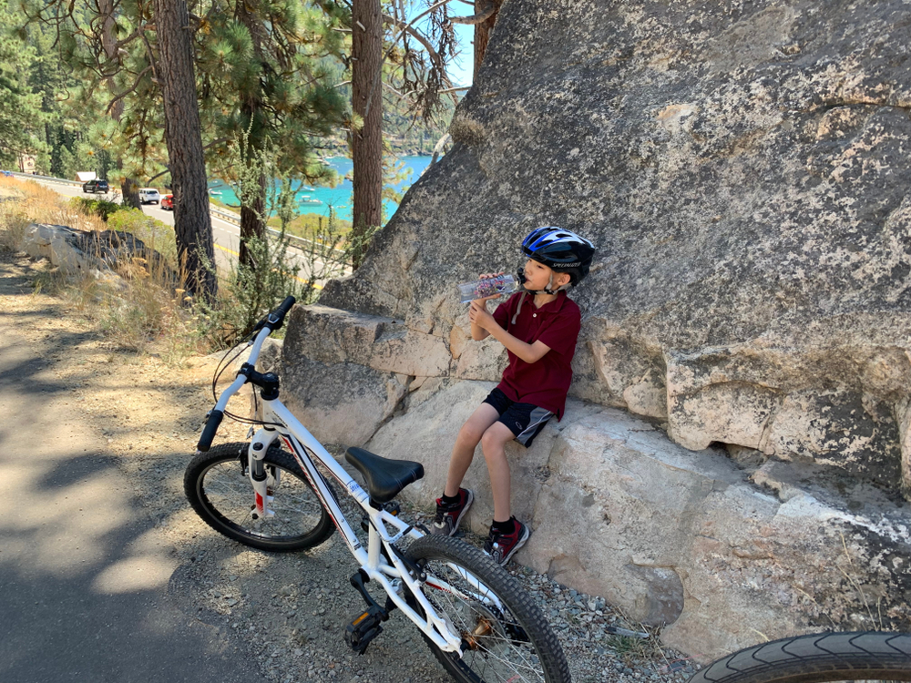 Featured image showing a young boy stopping for some water while biking near Lake Tahoe.