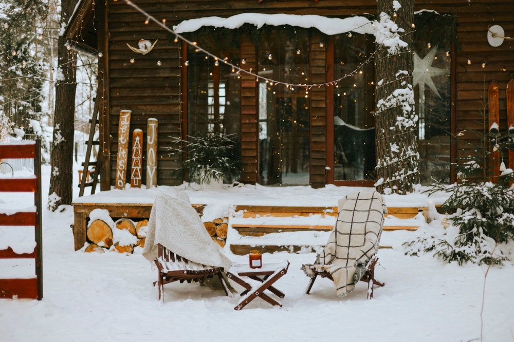 Featured image showing a cozy mountain home in the winter with outdoor seating, winter greenery and string lights to create curb appeal.