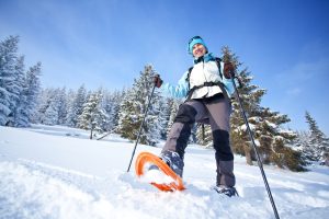 Featured image showing a happy snowshoer hiking in a snowy forest
