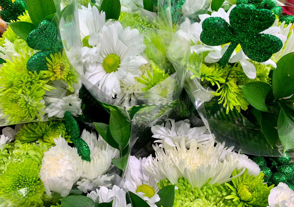 Inline image showing an elegant green and white floral arrangement with St. Patrick's Day accessories.