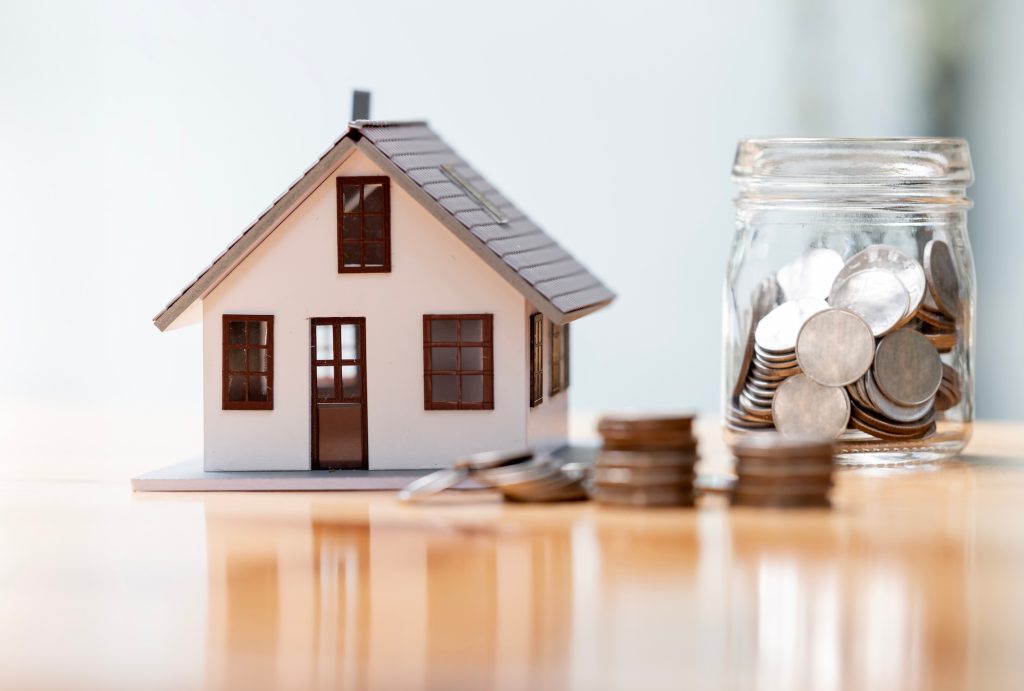 home-loans Inline image showing a tiny toy home next to a jar of coins.