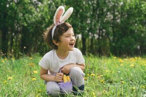 Featured image showing a cute little boy wearing bunny ears, having fun while hunting for Easter Eggs.